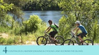 a man and a woman are riding bikes on a river